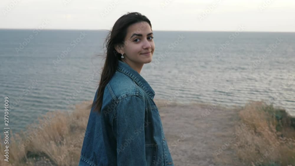 Young beautiful brunette girl walking on the mountain to the sea at sunset in slow motion Young beautiful brunette girl walking on the mountain to the sea at sunset in slow motion