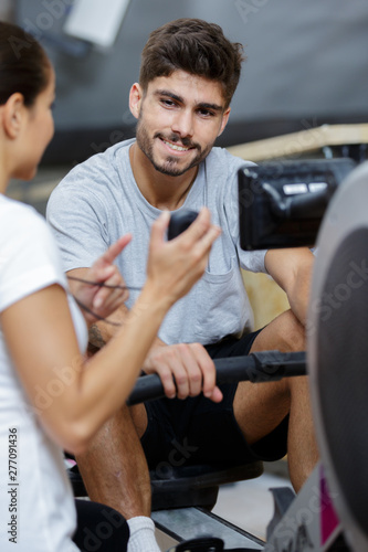 personal trainer showing time on stopwatch to man in gym