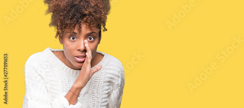 Beautiful young african american woman wearing winter sweater over isolated background hand on mouth telling secret rumor, whispering malicious talk conversation