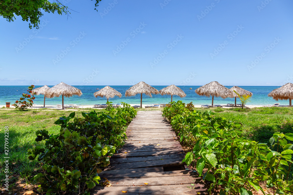Beautiful view of a wooden path leading to the sandy beach on the Caribbean Sea in Cuba during a bright and sunny day.