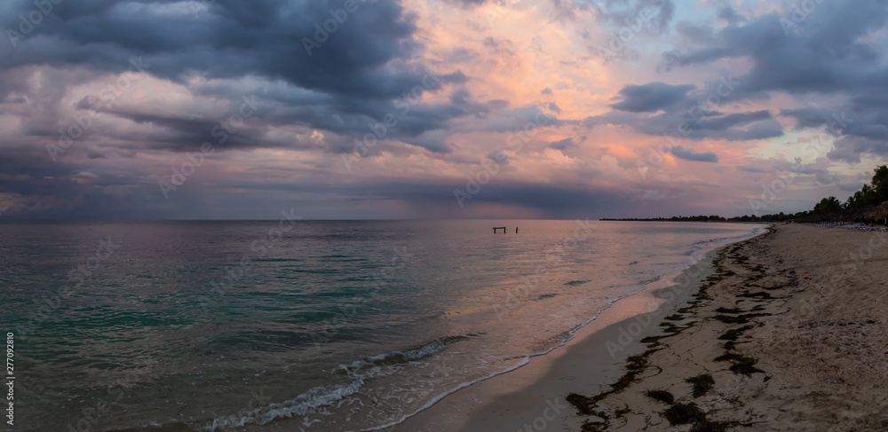 Beautiful Panoramic view of a sandy beach, Playa Ancon, on the Caribbean Sea in Triniday, Cuba, during a cloudy and rainy sunrise.