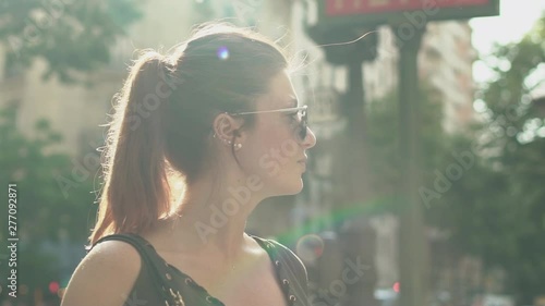 Attractive cool woman turning head at left then right and watching her smartphone at subway exit in street, during sunny summer in Paris. Beautiful rainbow in slow motion.