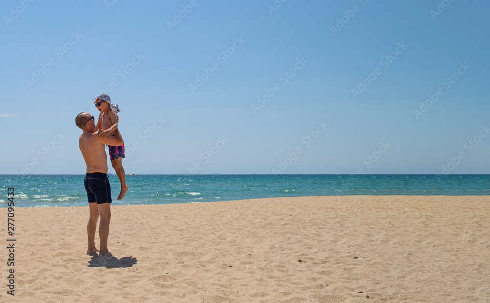Father and son on the beach on a clear day. People have fun in the fresh air. The concept of a summer holiday and a happy family. Father and son on the beach on a clear day. People have fun in the fresh air. The concept of a summer holiday and a happy family.