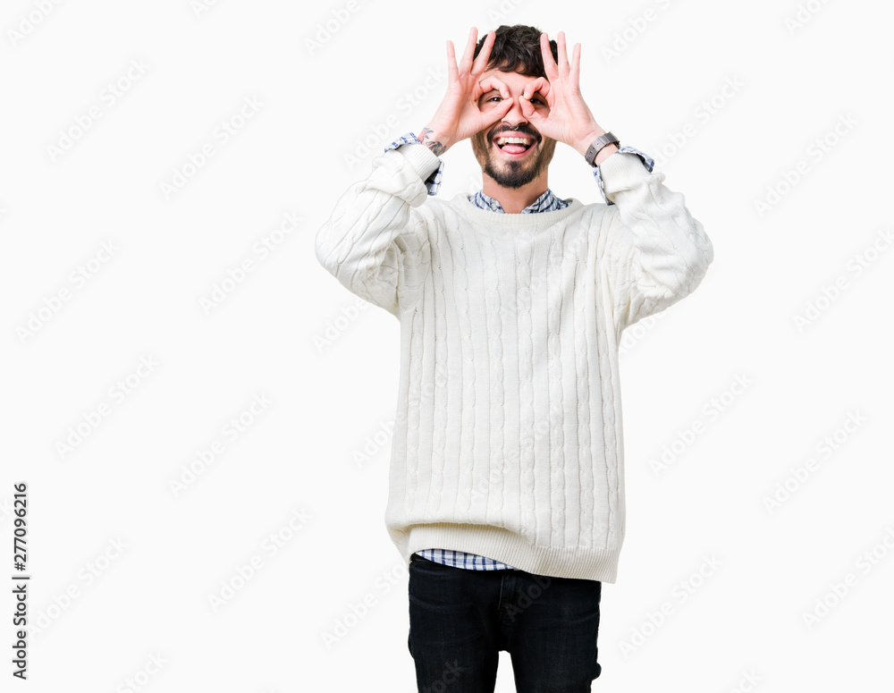 Fototapeta premium Young handsome man wearing winter sweater over isolated background doing ok gesture like binoculars sticking tongue out, eyes looking through fingers. Crazy expression.
