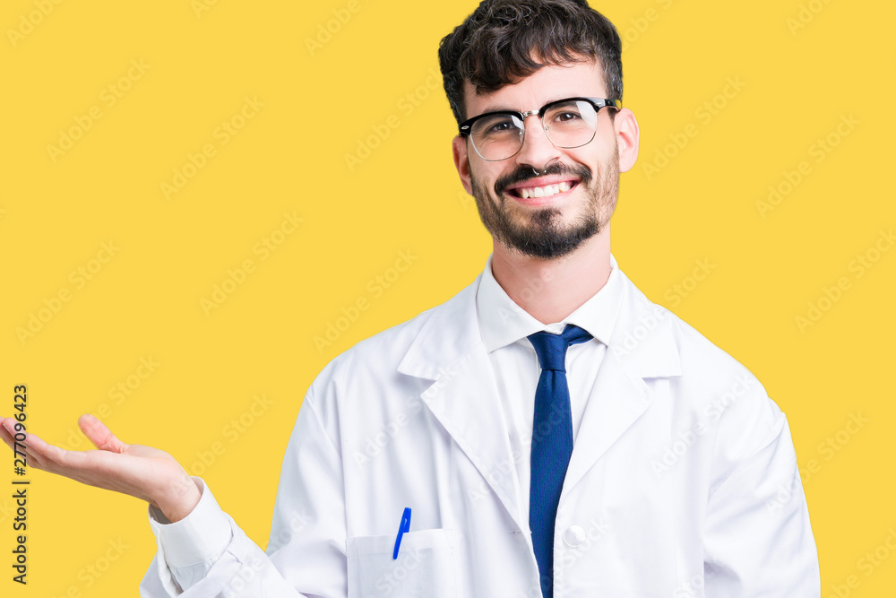 Young professional scientist man wearing white coat over isolated background smiling cheerful presenting and pointing with palm of hand looking at the camera. Young professional scientist man wearing white coat over isolated background smiling cheerful presenting and pointing with palm of hand looking at the camera.