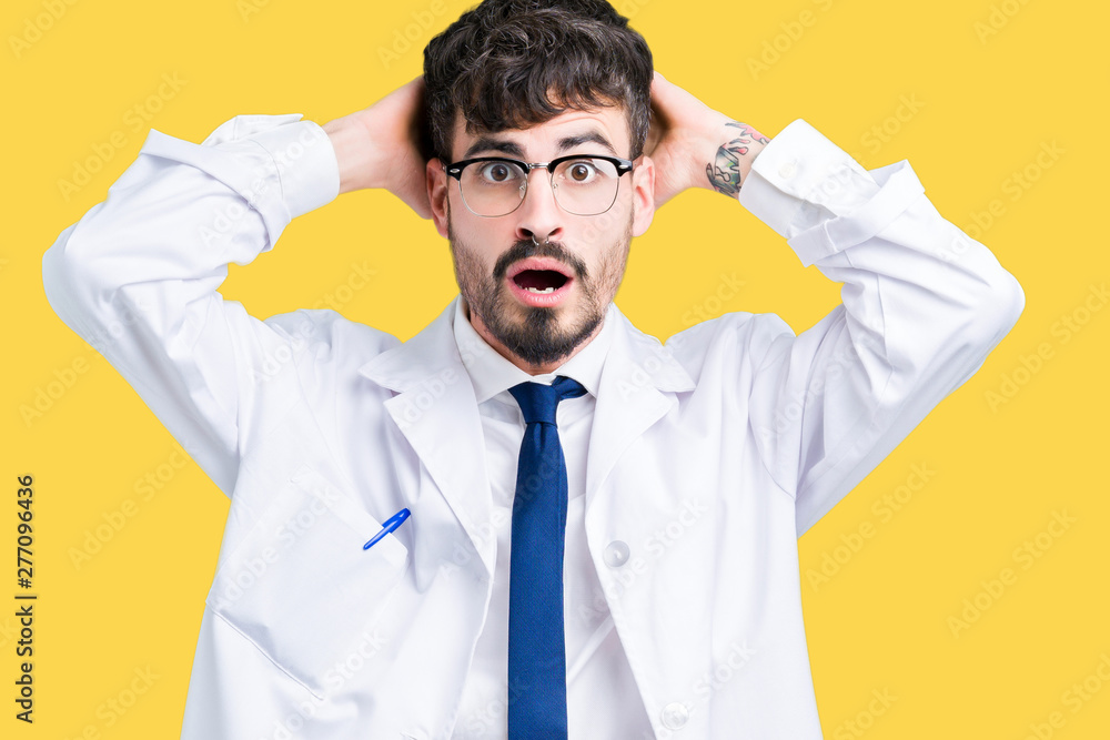 Young professional scientist man wearing white coat over isolated background Crazy and scared with hands on head, afraid and surprised of shock with open mouth Young professional scientist man wearing white coat over isolated background Crazy and scared with hands on head, afraid and surprised of shock with open mouth