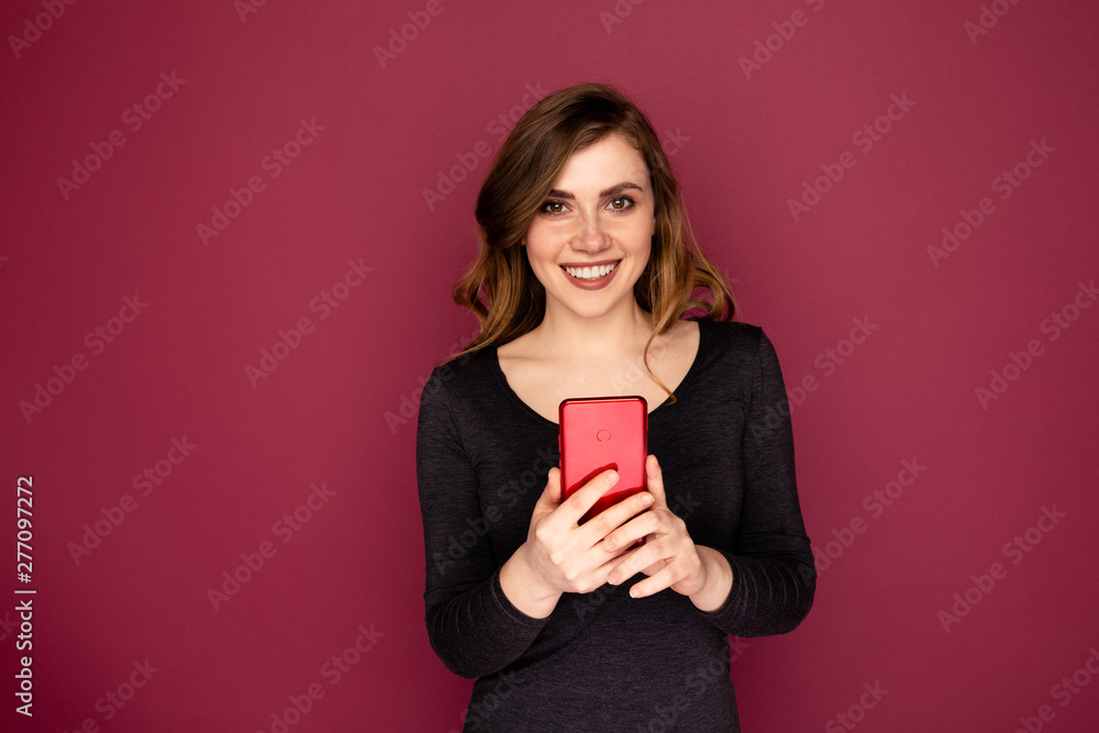 Young woman with red mobile isolated on the pink background Young woman with red mobile isolated on the pink background