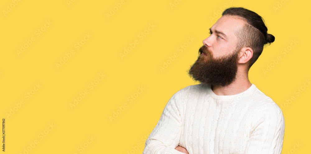 Young hipster man wearing winter sweater smiling looking to the side with arms crossed convinced and confident Young hipster man wearing winter sweater smiling looking to the side with arms crossed convinced and confident