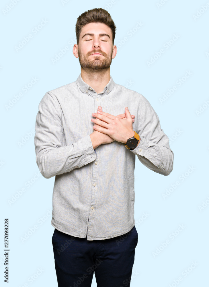 Young handsome man wearing casual shirt smiling with hands on chest with closed eyes and grateful gesture on face. Health concept. Young handsome man wearing casual shirt smiling with hands on chest with closed eyes and grateful gesture on face. Health concept.