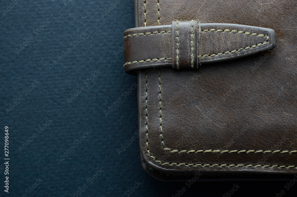 Wallet of rough brown leather, stitched with light-colored threads on a blue background Wallet of rough brown leather, stitched with light-colored threads on a blue background