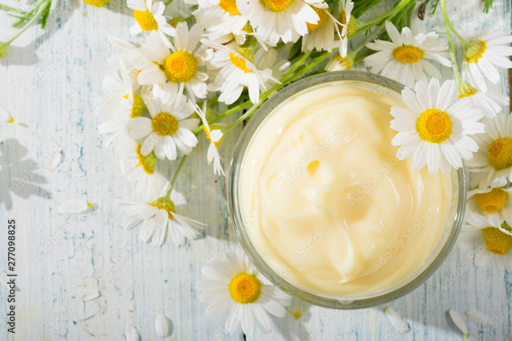 chamomile flowers and baby cream on white wooden table, directly above chamomile flowers and baby cream on white wooden table, directly above