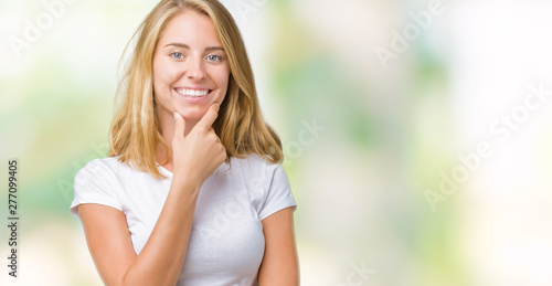 Beautiful young woman wearing casual white t-shirt over isolated background looking confident at the camera with smile with crossed arms and hand raised on chin. Thinking positive.