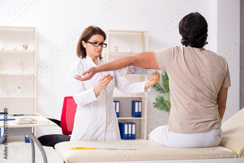 Tablou pe pânză Female doctor checking patient's joint flexibility with goniometer