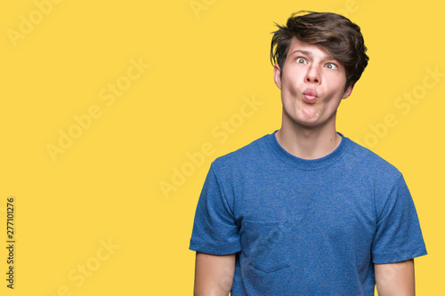 Young handsome man wearing blue t-shirt over isolated background making fish face with lips, crazy and comical gesture. Funny expression. © Krakenimages.com