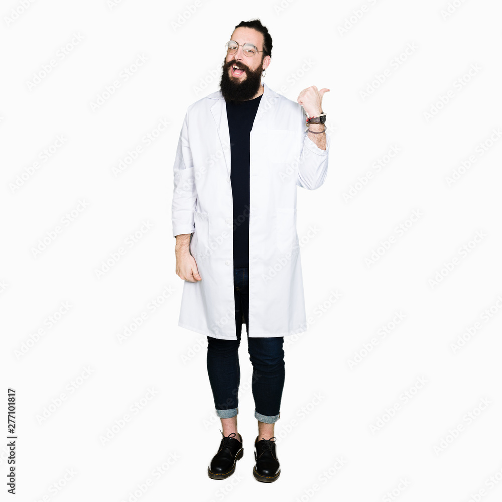 Doctor therapist man with long hair and bear wearing white coat smiling with happy face looking and pointing to the side with thumb up. Doctor therapist man with long hair and bear wearing white coat smiling with happy face looking and pointing to the side with thumb up.