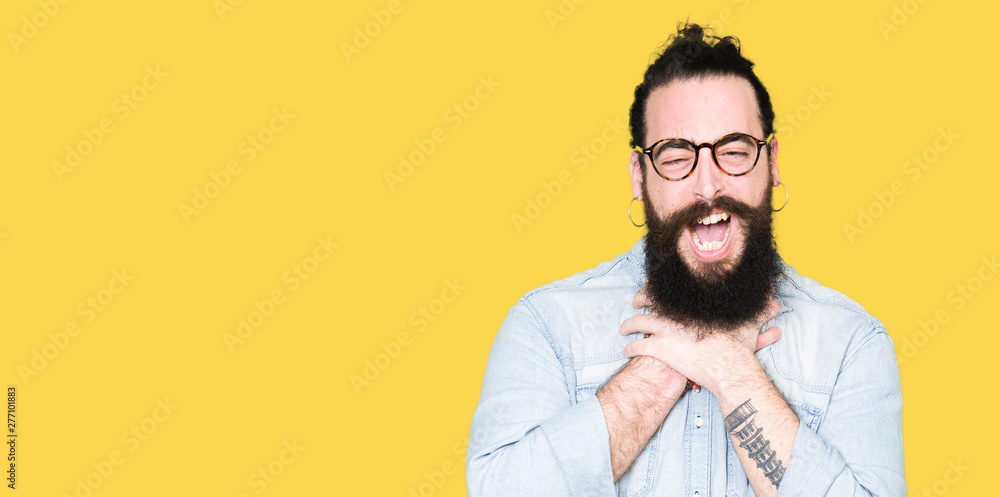 Obraz premium Young hipster man with long hair and beard wearing glasses shouting and suffocate because painful strangle. Health problem. Asphyxiate and suicide concept.