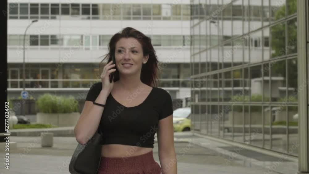 Woman having phone call walking in Business Center. Cute girl in Business District, Phone conversation, speaking at smartphone. Attractive Red hair freckles girl. Follow-up tight shot. Slow Motion. Woman having phone call walking in Business Center. Cute girl in Business District, Phone conversation, speaking at smartphone. Attractive Red hair freckles girl. Follow-up tight shot. Slow Motion.