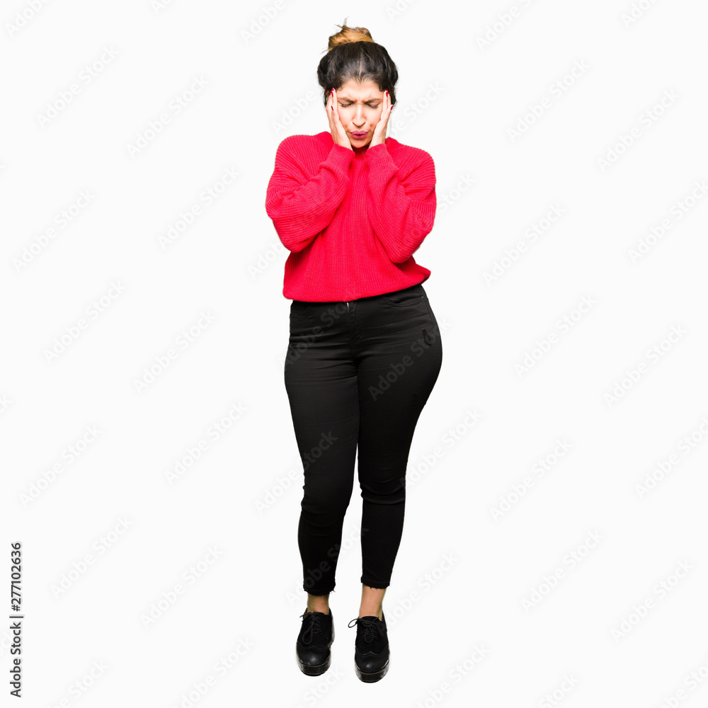 Young beautiful woman wearing red sweater and bun with hand on head for pain in head because stress. Suffering migraine. Young beautiful woman wearing red sweater and bun with hand on head for pain in head because stress. Suffering migraine.
