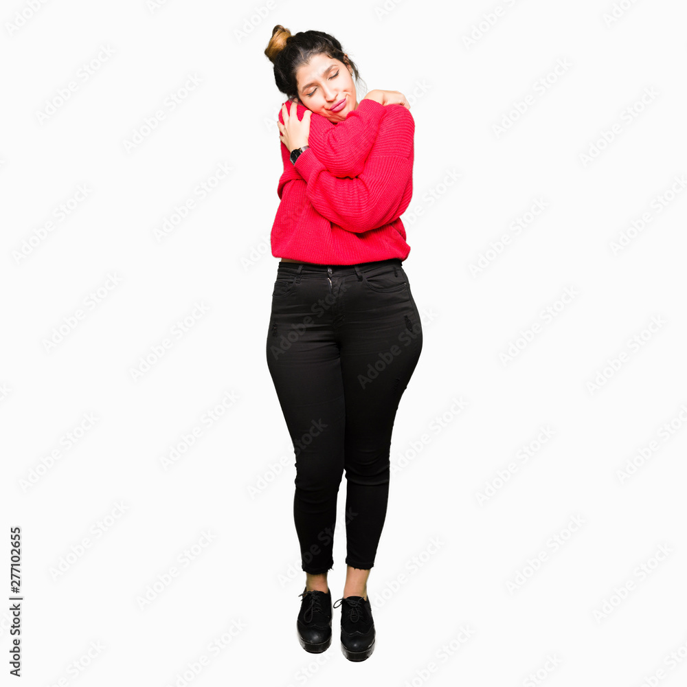 Young beautiful woman wearing red sweater and bun Hugging oneself happy and positive, smiling confident. Self love and self care Young beautiful woman wearing red sweater and bun Hugging oneself happy and positive, smiling confident. Self love and self care
