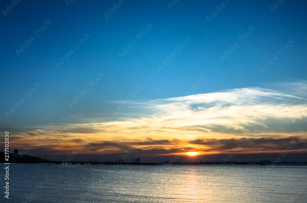 Sunset at sea with clouds and silhouette of island