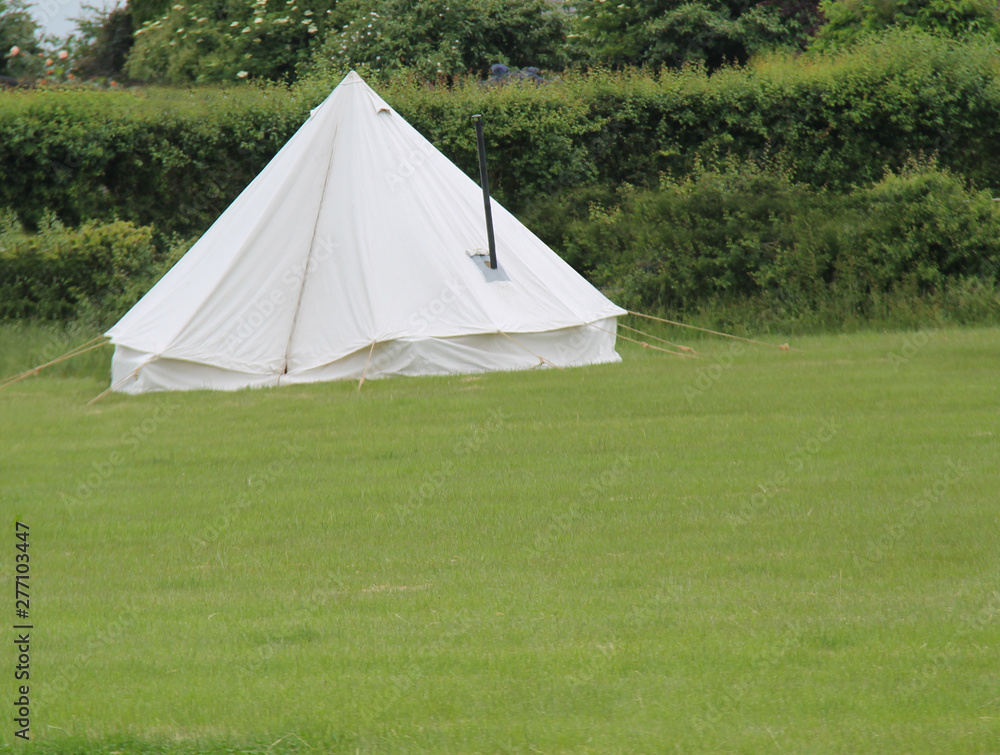 A White Canvas Bell Tent with a Metal Stove Chimney.