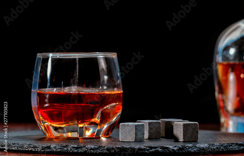 Glass of whiskey with black chilling cubes
