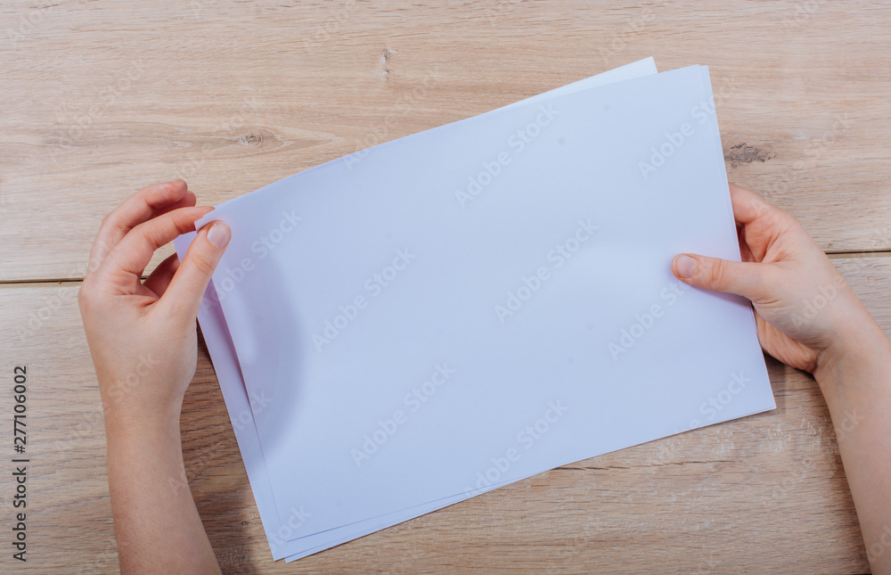 Hand holding sheets of paper on wooden background - obrazy, fototapety, plakaty 