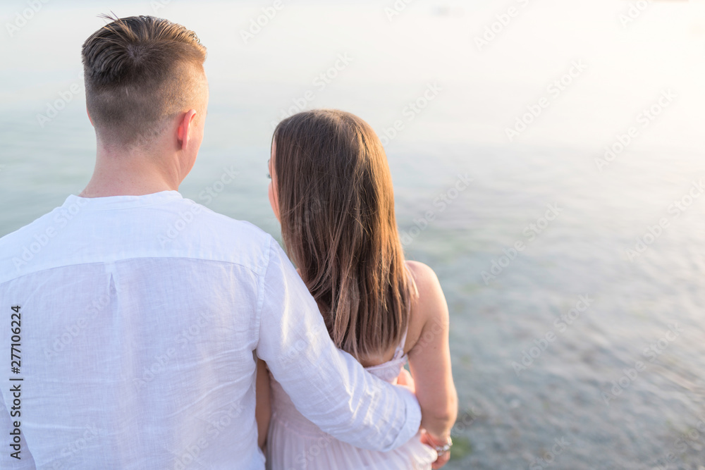 Summer couple embracing at sunset on beach. Romantic young couple enjoying sun, sunshine, romance and love by the sea. Closeup body foto