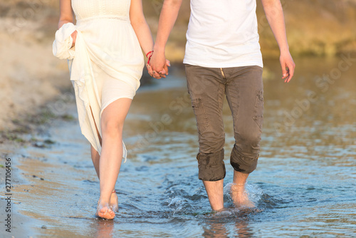 Couple holding hands walking romantic on beach on vacation travel holidays. Closeup of body and golden sand for copy space. Young loving couple