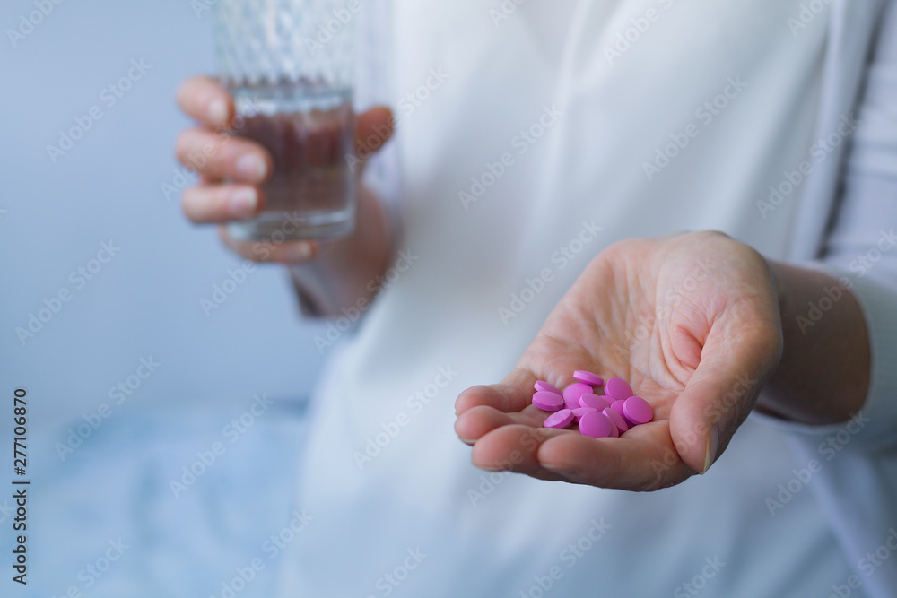 pink pills in hand with glass of water pink pills in hand with glass of water