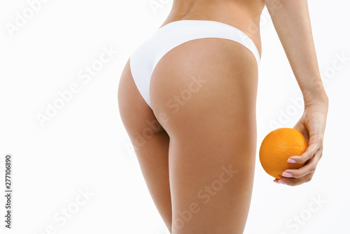 Beauty perfect slim body: fit sporty and healthy woman posing at white background in underwear with fresh orange. Sport, wellness, fitness, diet, weight loss and healthcare concept