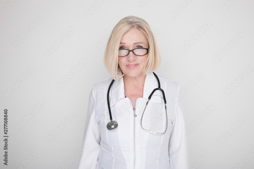 Woman doctor in glasses standing with stethoscope and looking in camera in a studio Woman doctor in glasses standing with stethoscope and looking in camera in a studio