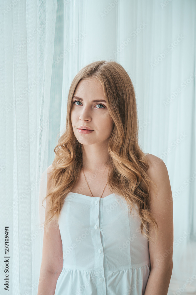 Girl in a light white dress posing by the window. Girl in a light white dress posing by the window.