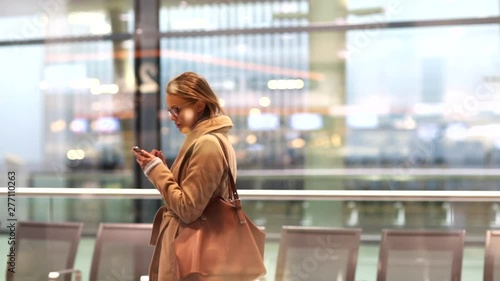 Young business female passenger at the airport, using her smart phone while waiting for her flight