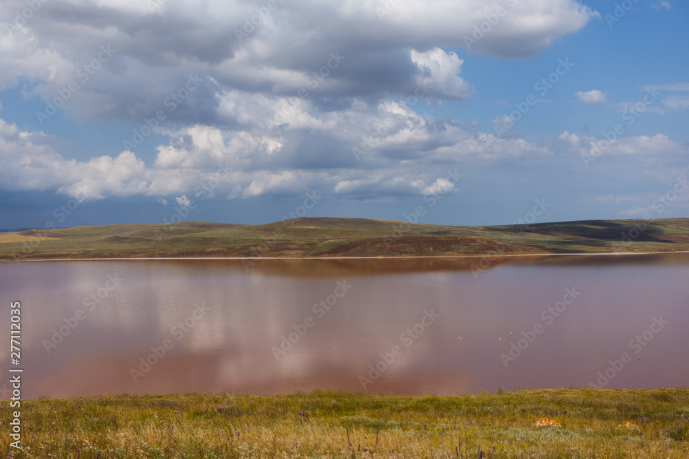 Pink Lake. Clouds are reflected in the water. Nebula-shaped clouds are floating across the sky. Summer sunny day. Pink Lake. Clouds are reflected in the water. Nebula-shaped clouds are floating across the sky. Summer sunny day.