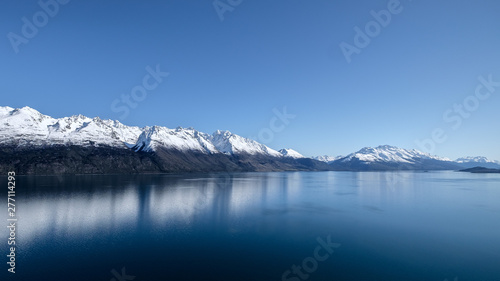 New Zealand travel image of Lake Wakatipu with snow mountain and blue mirror lake. Peaceful image of natural scenery during winter season in South island, New Zealand.