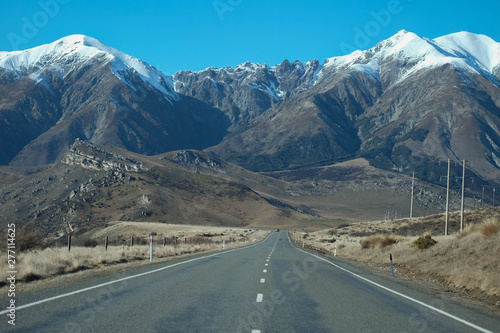 A long straight road leading towards a snow capped mountain in New Zealand.