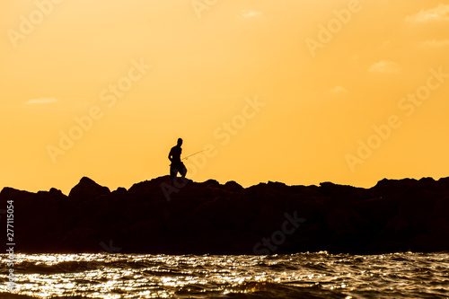 Man fishing on the rocks at the shore