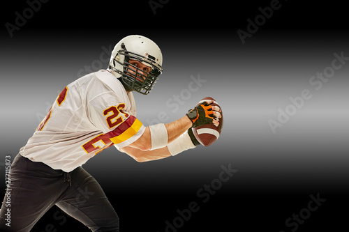 American football player in motion with the ball on a black background with a light line, copy space. The concept of the game is American football, movement.