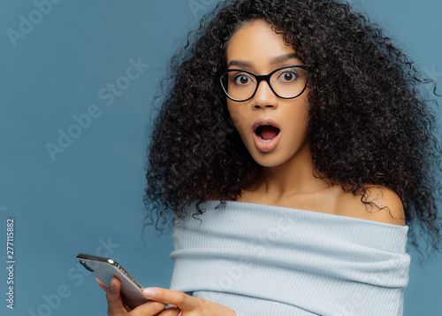 Fotografi Close up portrait of stupefied young woman with Afro hairstyle, keeps mouth wide