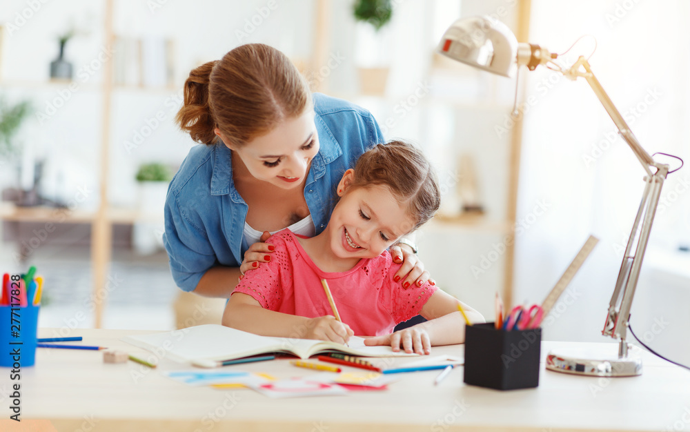 Fototapeta premium mother and child daughter doing homework writing and reading at home.
