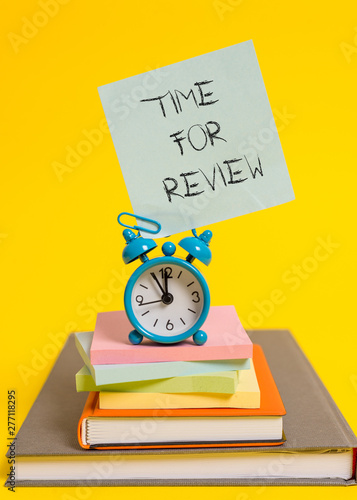 Handwriting text writing Time For Review. Conceptual photo review of a system or situation in its formal examination Alarm clock note stacked notepads old books colored background photo