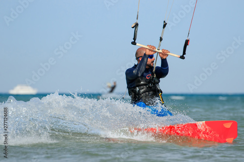 Professional kite boarding rider sportsman with kite rides blue lagoon smiling enjoying fun joy happy leisure rest relaxing time. Recreational activity, extreme active air water sports on sea. Man