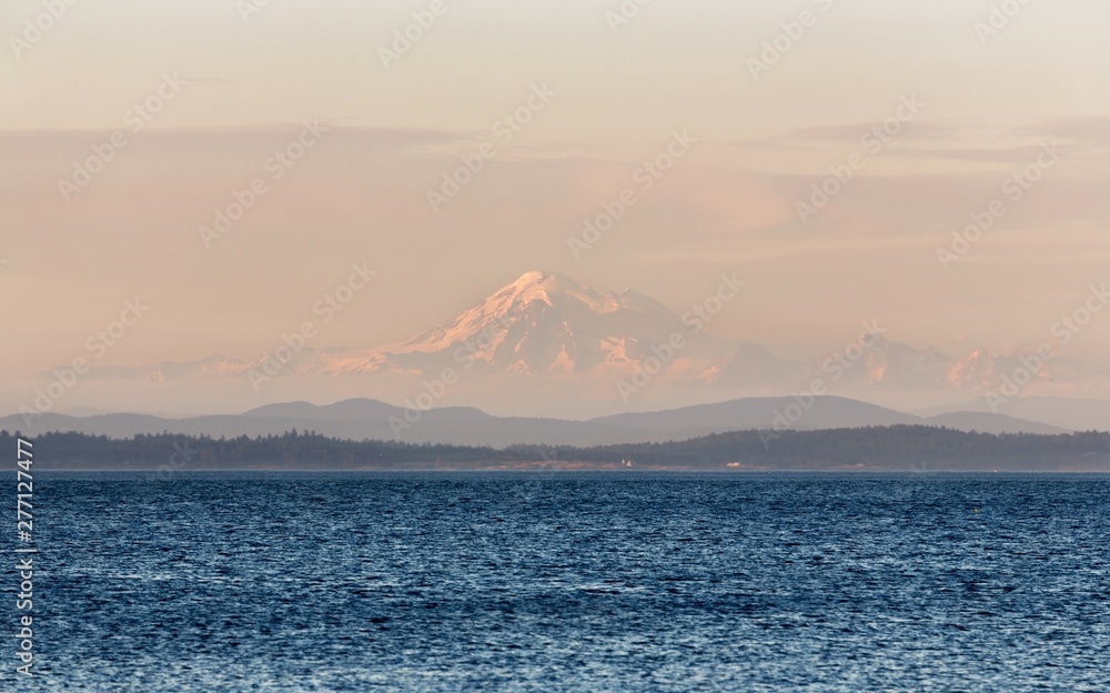 Scenic Landscape View of Distant Mount Baker near Seattle, Washington USA seen through haze during Sunset from Oak Bay on Vancouver Island, BC Canada