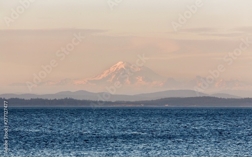 Scenic Landscape View of Distant Mount Baker near Seattle, Washington USA seen through haze during Sunset from Oak Bay on Vancouver Island, BC Canada