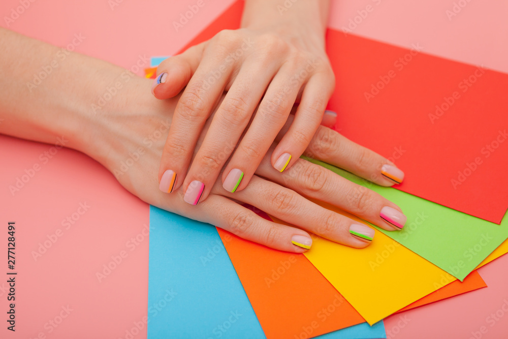 Fototapeta premium Modern stylish manicure rainbow or summer mood, on a pink table with color envelopes. Close-up