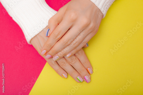Stylish trendy female manicure. Beautiful young woman s hands on pink and yellow background.
