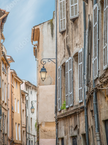 Streetlights hang from leaning, crumbling ancient buildings on a narrow residential street in France 