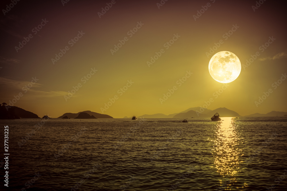 Scenic view of small boat in calm sea water at night time and super moon.