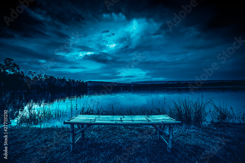 Obraz na płótnie bamboo litter on grass in front of lake and moonlight behind a cloudy at night time w salonie